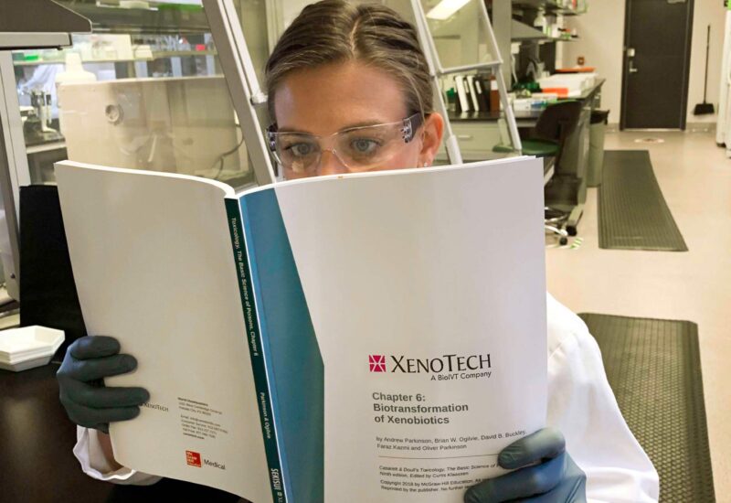 Lab researcher reading Xenotech biotransformation of xenorobotics book